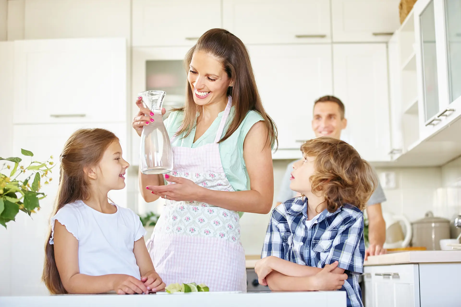 Family in their kitchen pouring a pitcher of clean, tested drinking water