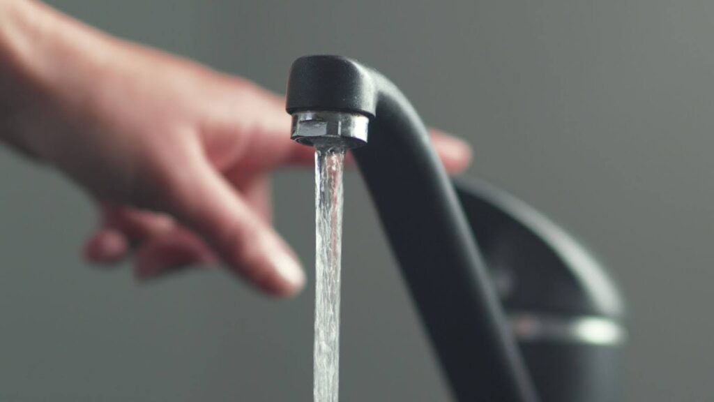 tap water pouring from a black chrome kitchen faucet