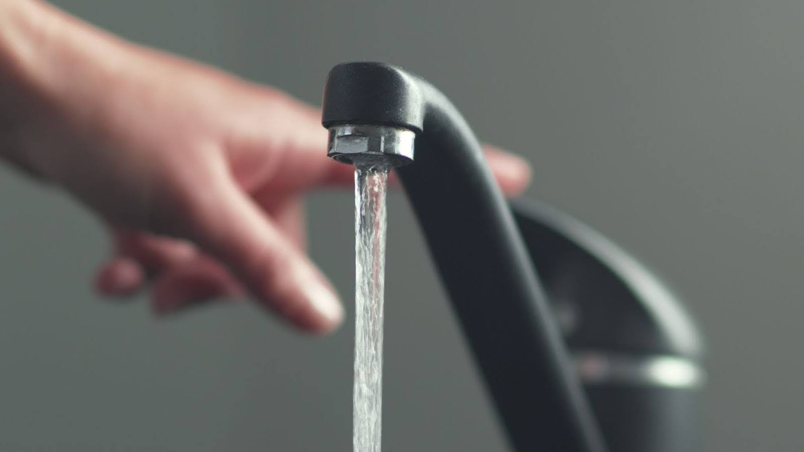 tap water pouring from a black chrome kitchen faucet
