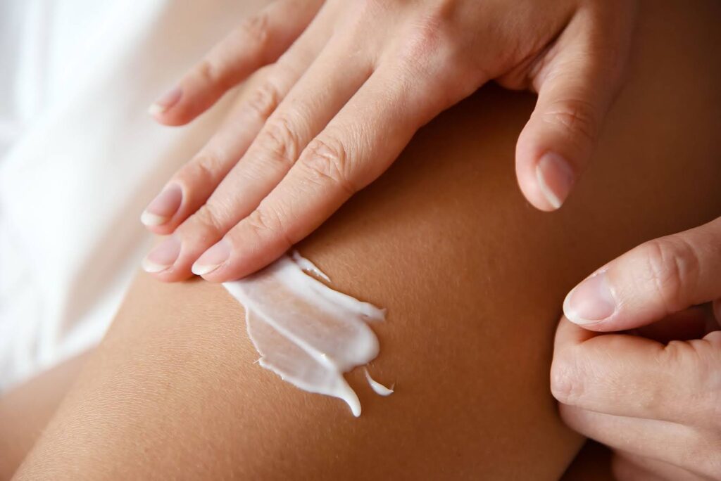 A woman's hand massaging lotion onto her legs
