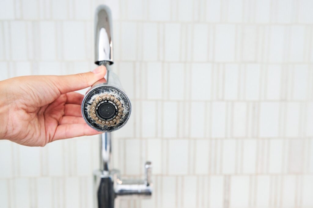 A kitchen faucet with limescale around the water spout