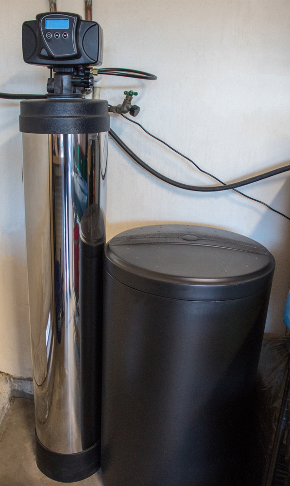 A residential water softener sitting next to a black salt tank