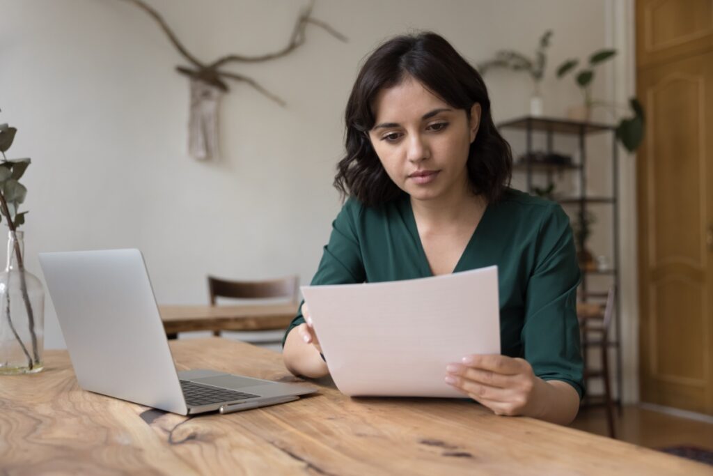 a female homeowner sitting in front of her laptop at the kitchen table as she does research on the best warranties for water softeners